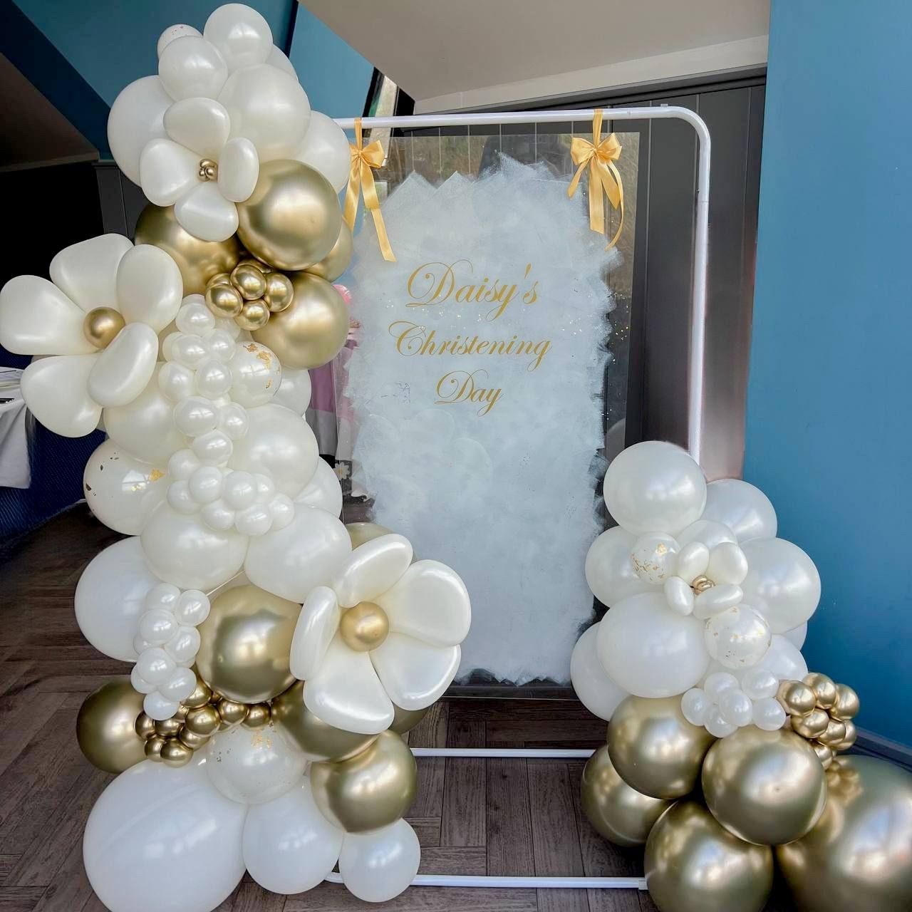 Decorative balloon arch with white and gold balloons at a christening event.