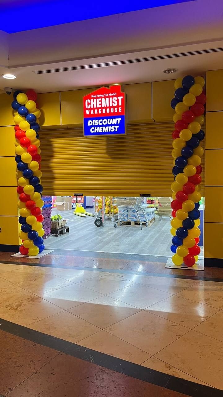 Shop entrance with balloon decorations and partially open yellow shutter displaying a trolleys inside.