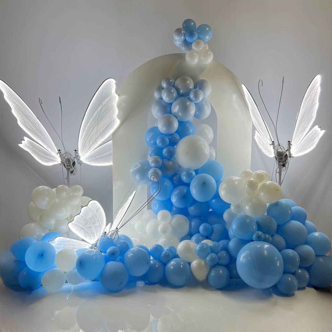 Decorative arrangement of blue and white balloons with illuminated butterfly figures.