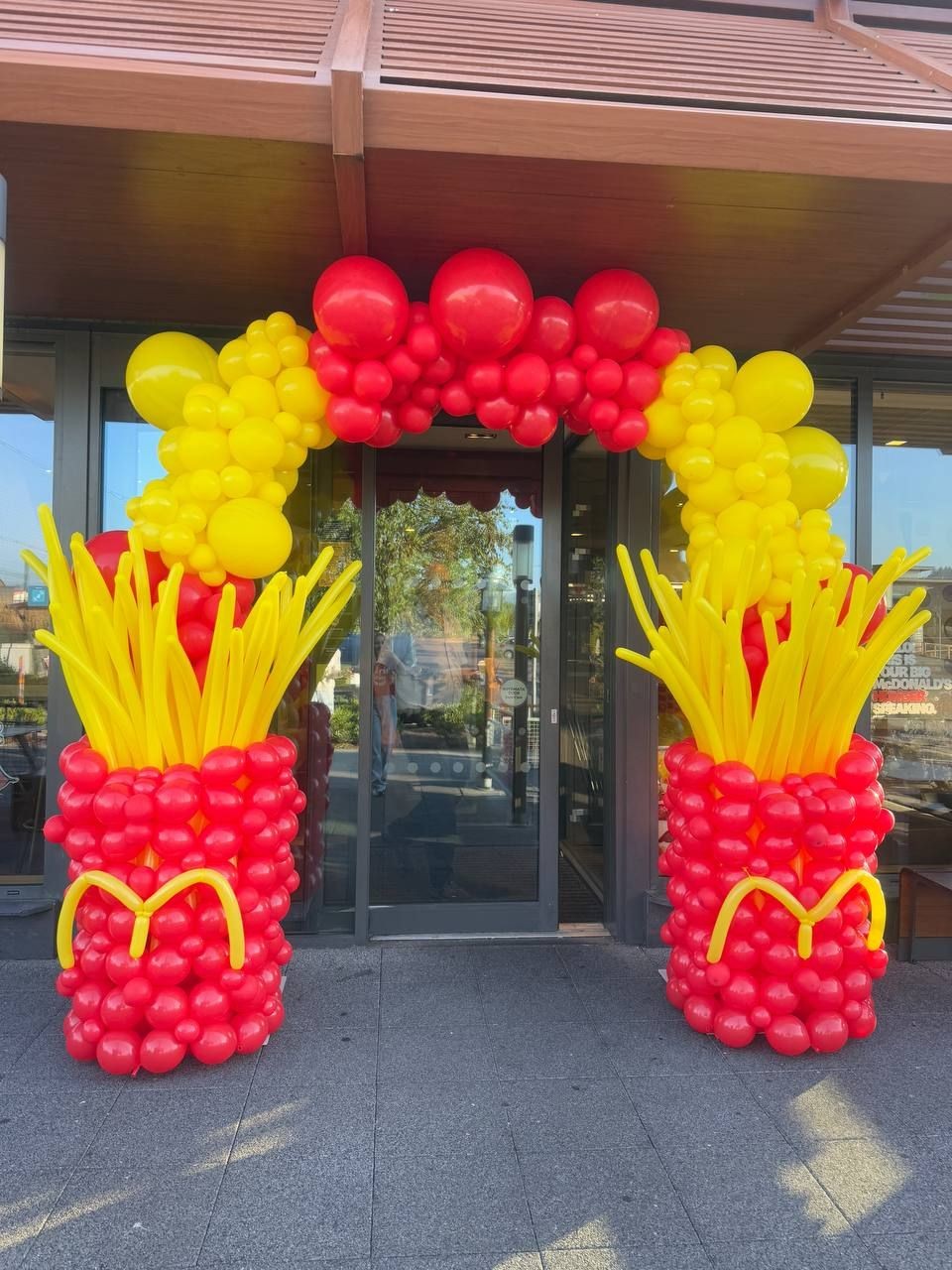Entrance decorated with red and yellow balloon arch resembling French fries and containers.